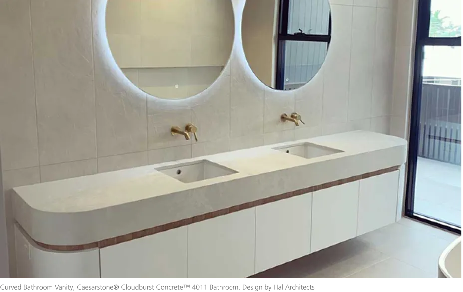 Modern bathroom with a curved Caesarstone thermoformed vanity top, dual sinks, and round backlit mirrors.