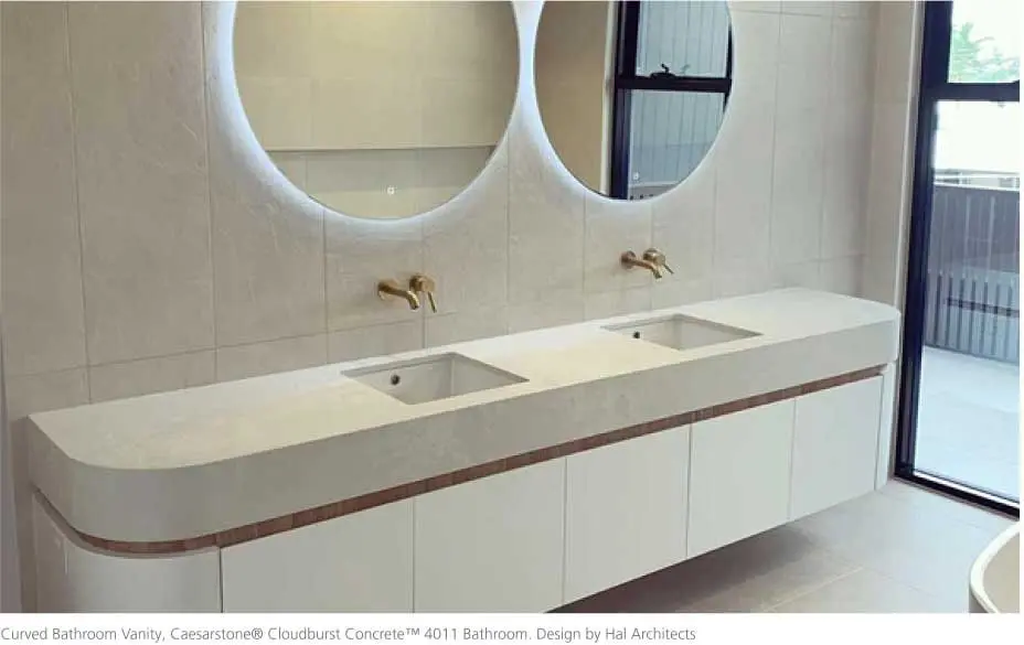 Modern bathroom with a curved Caesarstone thermoformed vanity top, dual sinks, and round backlit mirrors.