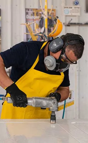 Icon Fabrication and Installation Guide cover with fabricator wearing protective gear and yellow apron uses power tool on a white surface.