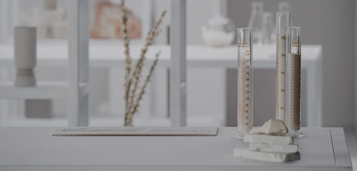 Laboratory setup showcasing Caesarstone Advanced Fusion Surfaces with glass cylinders, raw minerals, and stone samples on a clean white table.